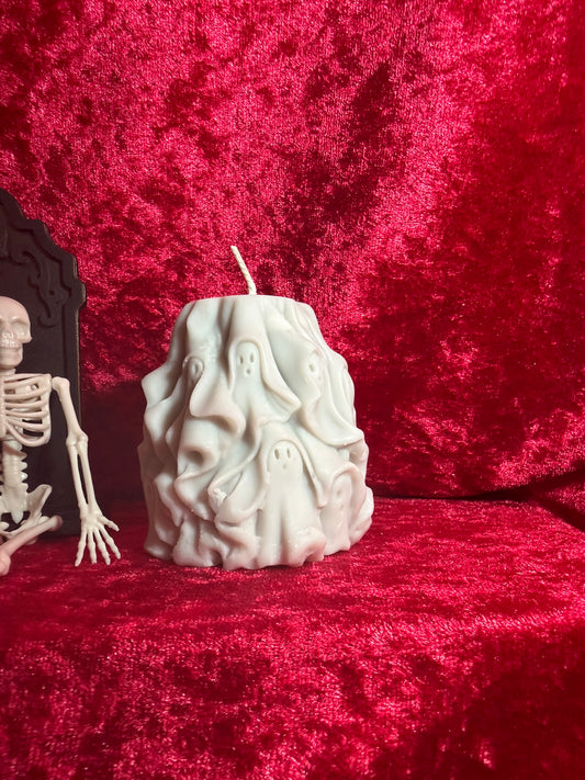 White sculpted ghost-stack pillar candle on a red fabric backdrop.